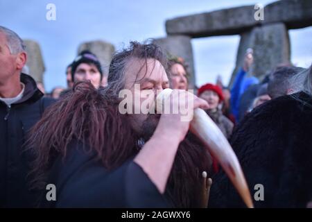 A man drinks mead from an animal horn inside the stone circle at Stonehenge in Wiltshire to mark the winter solstice. Stock Photo