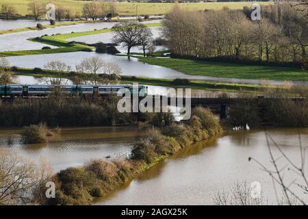 Lewes UK 22nd December 2019 - A train passes over flooded fields just north of Lewes in East Sussex after overnight rain as more weather and flood warnings have been issued across Britain after days of continual rain : Credit Simon Dack / Alamy Live News Stock Photo