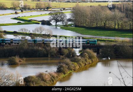 Lewes UK 22nd December 2019 - A train passes over flooded fields just north of Lewes in East Sussex after overnight rain as more weather and flood warnings have been issued across Britain after days of continual rain : Credit Simon Dack / Alamy Live News Stock Photo