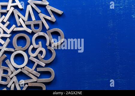 Flat mockup of silver metal alphabet characters on blue painted board background with copyspace. Stock Photo