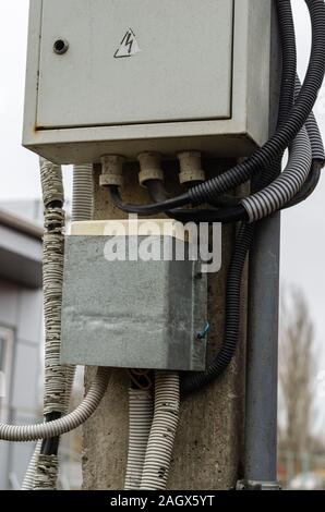 An old electrical panel Electric cables in protective corrugations. Selective focus. Without people. The vertical arrangement of the photo. Stock Photo