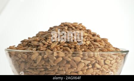Nuts sunflower rotate are on a table in a plate. Snack in transparent dish on an isolated white background are spinning moving. Stock Photo