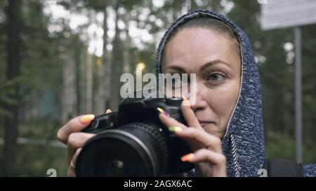 Traveler photographing scenic view in forest. One caucasian woman shooting close up look. Girl take photo video on dslr mirrorless camera. Stock Photo