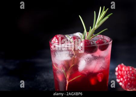 Pomegranate Rosemary Holiday Christmas cocktail with sparkling wine, cranberry, club soda on black table. Close up. Stock Photo