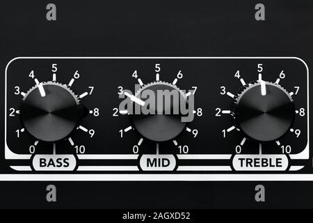 Close up detail of sound equalizer control knobs of a black guitar amplifier. Bass, mid and treble knobs. Stock Photo