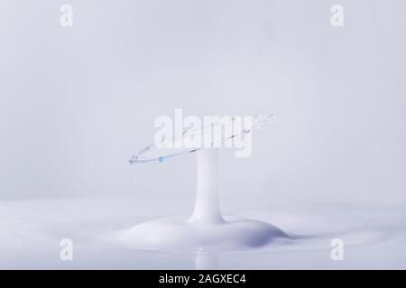 A macro photo of two drops of blue food coloring in a pool of thick creamy milk captured using a flash to freeze the motion Stock Photo
