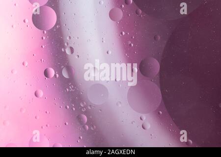 An abstract artistic close up macro photo created by mixing oil and water then back lit with a pinky magenta flash Stock Photo