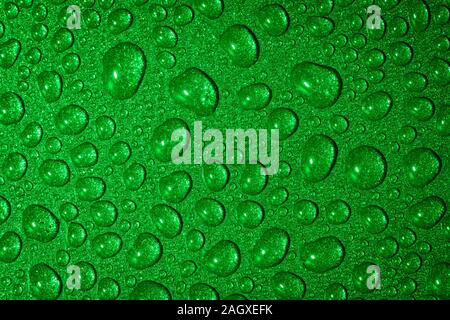 A close up abstract macro photo of water droplets on a grey non stick frying pan material lit with a green flash gel Stock Photo