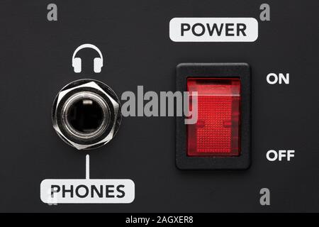 Power on and off electrical switch button and headphone input jack on a black amplifier. Listening to music without disturbing. Close up detail. Stock Photo