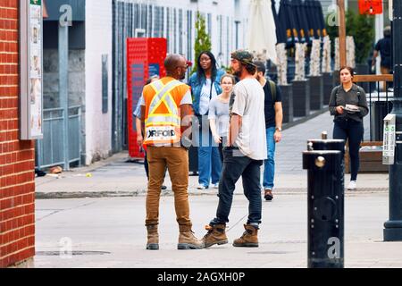Montreal, Canada - June, 2018: Two Canadian municipal construction workers talking on the street in Montreal, Quebec, Canada. Stock Photo