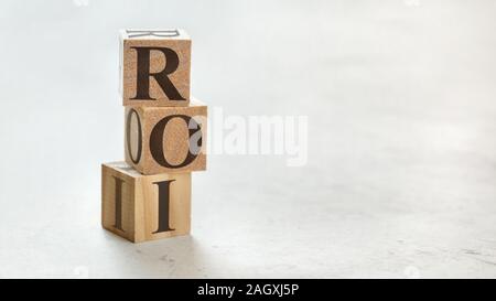 Pile with three wooden cubes - letters ROI meaning Return on Investment on them, space for more text / images at right side. Stock Photo