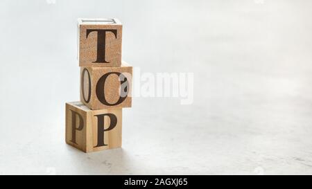 Pile with three wooden cubes - word TOP on them, space for more text / images at right side. Stock Photo