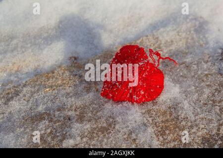 Red woolen heart on a snowy wooden surface, Valentine's Day Stock Photo