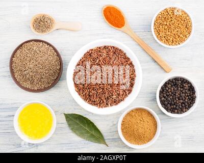 Ingredients for cooking brown rice: butter, bay leaves, cumin (jeera), fenugreek, red chili pepper, masala, black pepper. Healthy eating concept Stock Photo