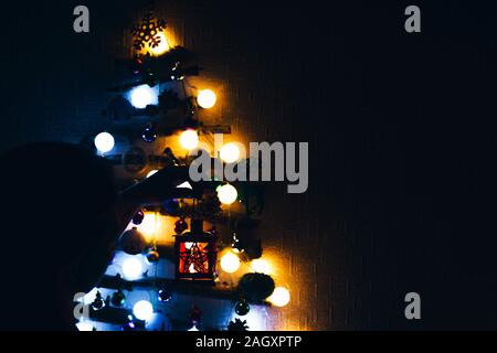 Christmas Eve. The night tree glows in the dark with blue and orange flowers, and the girl waits for Santa Claus. Stock Photo