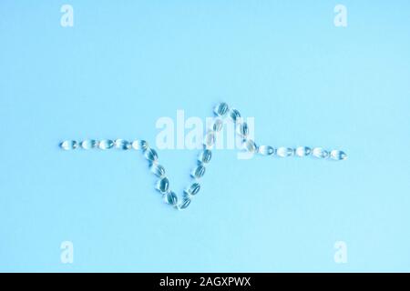 Lozenges scattered in the shape of a heartbeat on a blue background Stock Photo