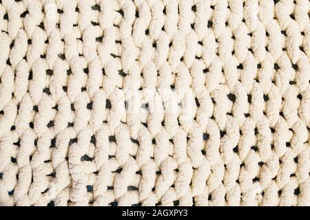 Beige yarn blanket on the bed. Texture background. Stock Photo