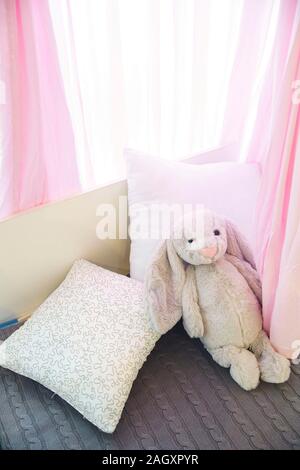 Cute bunny toy on bed in baby room Stock Photo