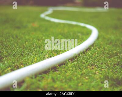 White watering hoses on a green lawn. Tone Stock Photo