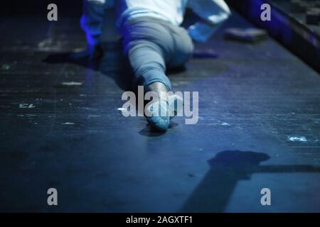 The leg of a dancer doing stretching on the floor of a rehearsal room Stock Photo