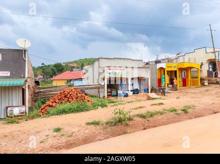 Typical low-rise roadside village shops including a vet drug shop and buildings for local people in the Western Region of Uganda, on a cloudy day Stock Photo