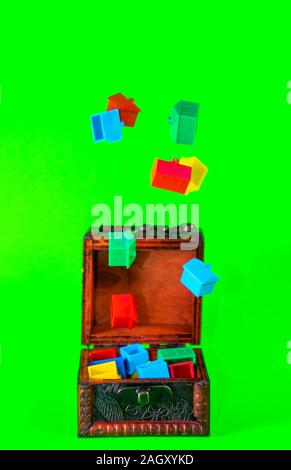 A wooden chest full of plastic houses, taken against a green screen background. Stock Photo