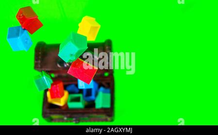 A wooden chest full of plastic houses, taken against a green screen background. Stock Photo