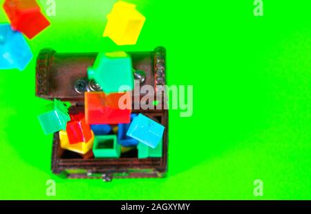 A wooden chest full of plastic houses, taken against a green screen background. Stock Photo