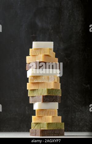 Tower stack of different kinds of handmade solid soap bars and shampoo over grey background Stock Photo