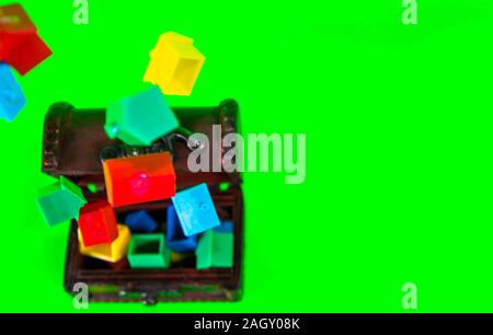 A wooden chest full of plastic houses, taken against a green screen background. Stock Photo