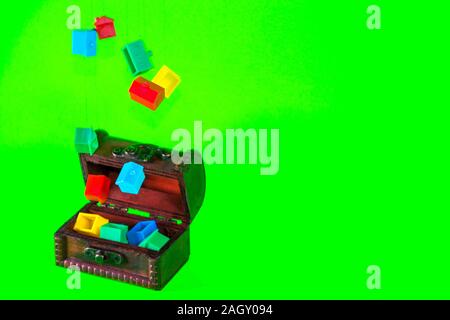 A wooden chest full of plastic houses, taken against a green screen background. Stock Photo