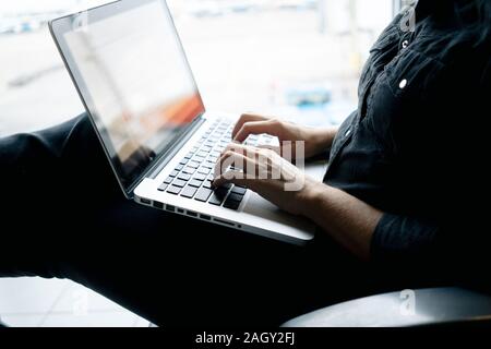 A caucasian blond woman waits at the airport working with her laptop Stock Photo