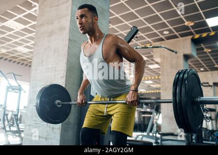 Athletic man doing exercise with barbell in gym Stock Photo