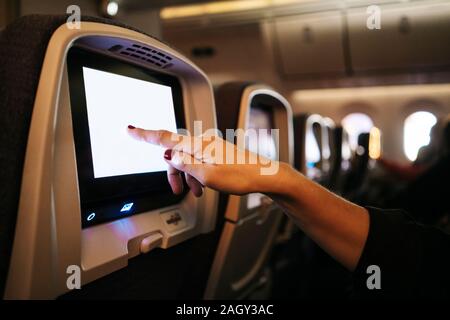 Detail of a woman's hands using the touch screen of an airplane Stock Photo