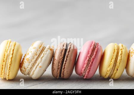 Colorful macaroon cakes in a row over grey background Stock Photo