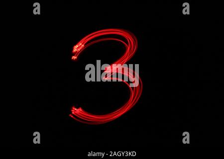 Light painting photograph of a number, drawn by fairy lights in red vibrant neon color against a black background.  Long exposure photography. Stock Photo