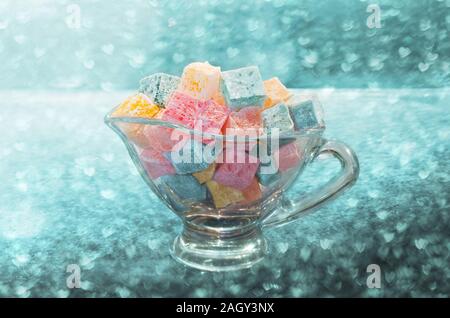 Turkish delight small colorful cubes in a glass bowl, on the background of bokeh Stock Photo