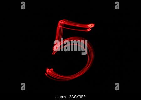 Light painting photograph of a number, drawn by fairy lights in red vibrant neon color against a black background.  Long exposure photography. Stock Photo