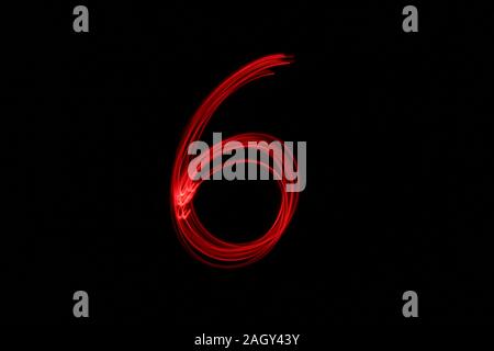 Light painting photograph of a number, drawn by fairy lights in red vibrant neon color against a black background.  Long exposure photography. Stock Photo