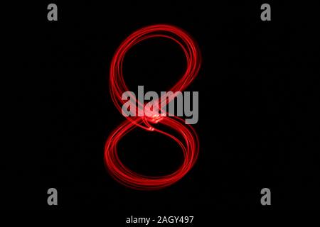 Light painting photograph of a number, drawn by fairy lights in red vibrant neon color against a black background.  Long exposure photography. Stock Photo