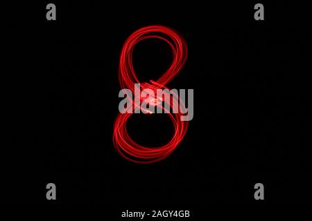 Light painting photograph of a number, drawn by fairy lights in red vibrant neon color against a black background.  Long exposure photography. Stock Photo