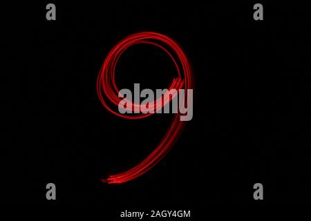 Light painting photograph of a number, drawn by fairy lights in red vibrant neon color against a black background.  Long exposure photography. Stock Photo