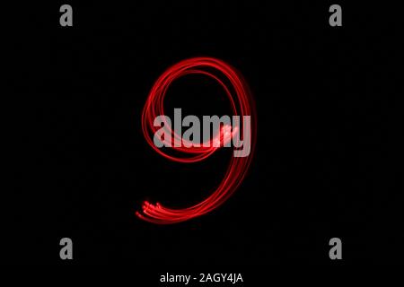 Light painting photograph of a number, drawn by fairy lights in red vibrant neon color against a black background.  Long exposure photography. Stock Photo