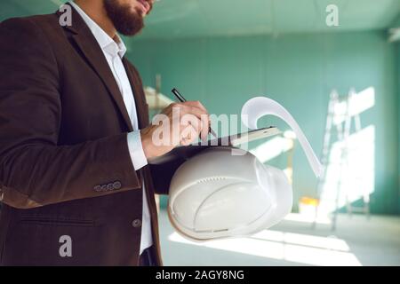 Construction foreman writes on paper indoors at a construction site in the room. Construction concept. Stock Photo