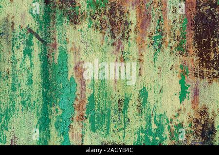 Old metal rusted green-yellow sheet with bounced, cracked paint. Abstract colorful texture background. Stock Photo