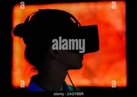 Young woman using virtual reality headset at dark interactive exhibition Stock Photo