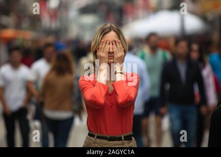 Woman covers his eyes during panic attack in public place. Stock Photo