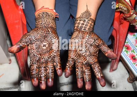 Photo of Intricate hand mehndi design with bride and groom portrait