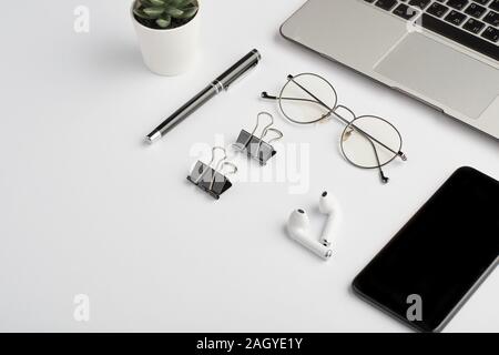 Wireless earphones, eyeglasses, pen, clips, mobile phone and laptop keypad Stock Photo