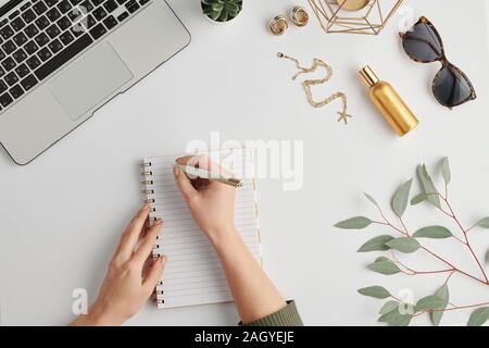 Hands of businesswoman holding pen over blank page of notebook Stock Photo